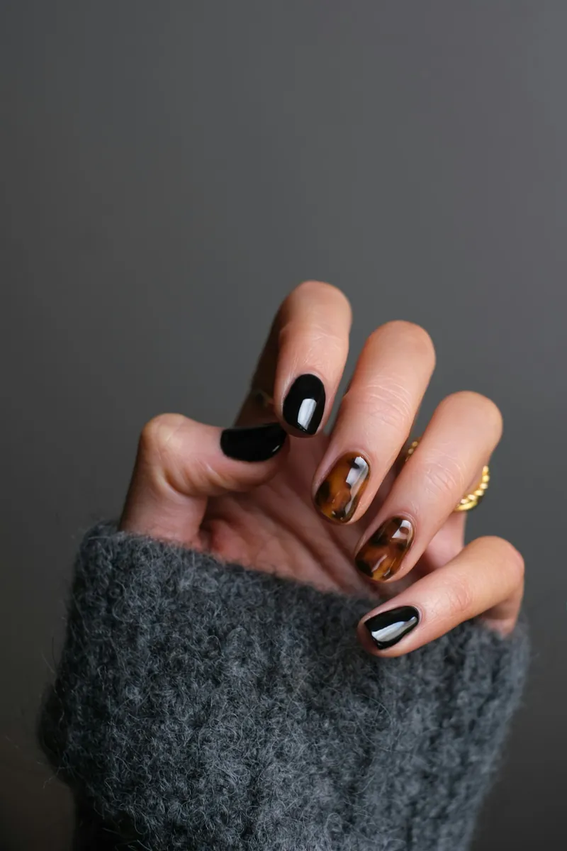 Czarny manicure ze zdobieniem w bursztynowym kolorze